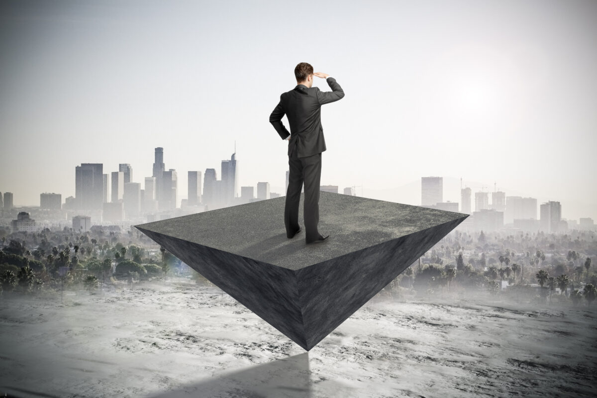 都市を見渡しながら未来を見据えるビジネスマンのイメージ。投資や経済の安定を長期視点で考える象徴的な構図