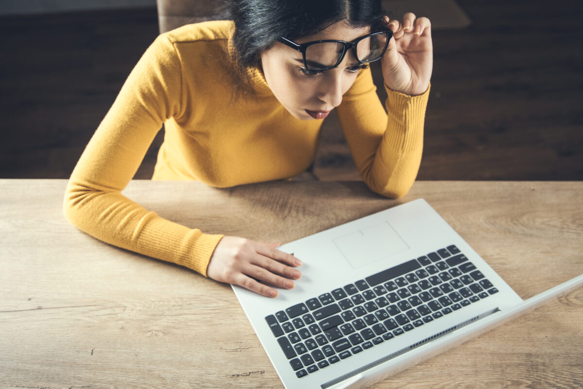 パソコンで投資情報を調べながら真剣に考える女性