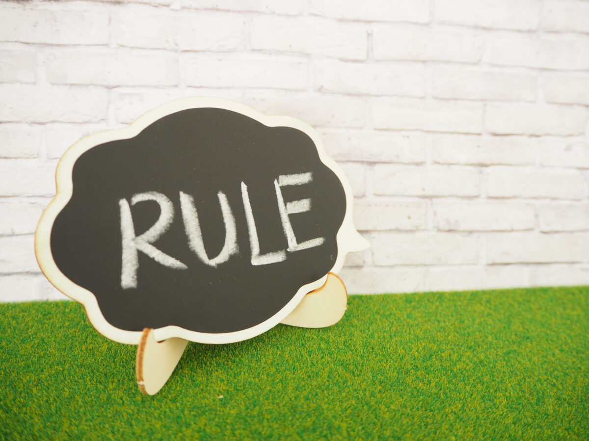 投資や資産運用で大切なルールを表すイメージ写真。黒板に「RULE」と書かれたボードが芝生の上に置かれている